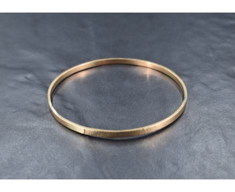 A yellow metal bangle, marked 9ct having alternating panels of textured and plain design, approximately 20cm inner circumfere