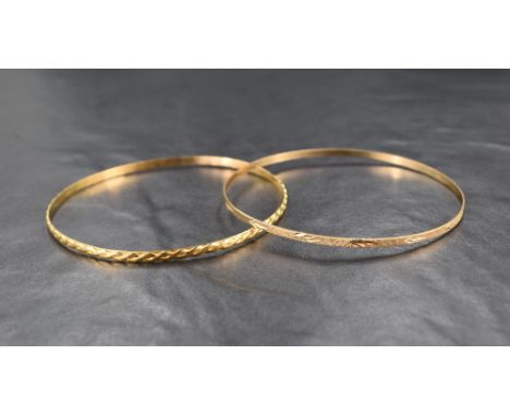 An 18ct gold bangle, having an embossed rope motif, sold along with a 9ct gold bangle, having a textured and floral engraved 