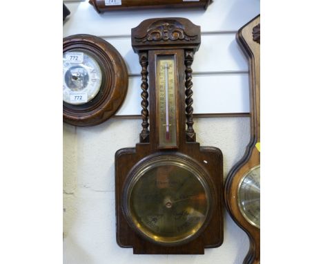 An oak carved aneroid barometer with thermometer above