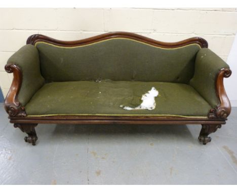 A Victorian upholstered sofa with scrolling arms and legs and carved decoration, raised on brass castors