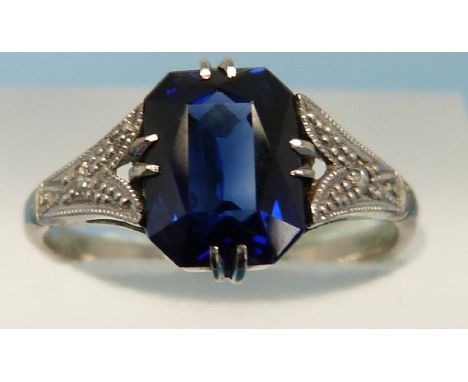 A white metal ring marked 18ct & platinum set with a sapphire of approximately 1.9ct with a diamond to each shoulder (size K)