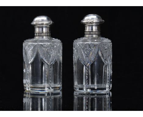 A pair of early 20thC Fabergé glass bottles with pull-off silver tops, lightly domed with embossed reed and ribbon girdles ab