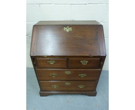 A small Georgian oak bureau, the fall flap opening to reveal pigeon holes and drawers, the base fitted two over two drawers w