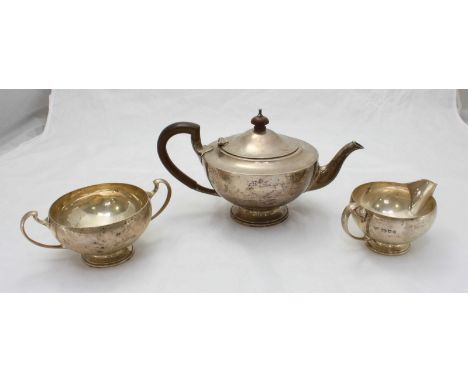 A Three piece Silver tea set retailed by Harrods, comprising tea pot, sugar bowl and milk jug, the teapot with wooden handle 