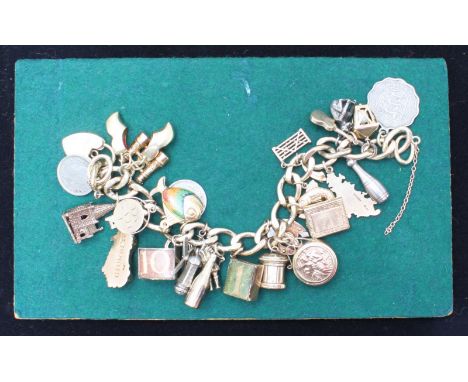 A 9ct gold charm bracelet with approximately 29 charms, most being gold, including a compass, post box, Bible and heart locke