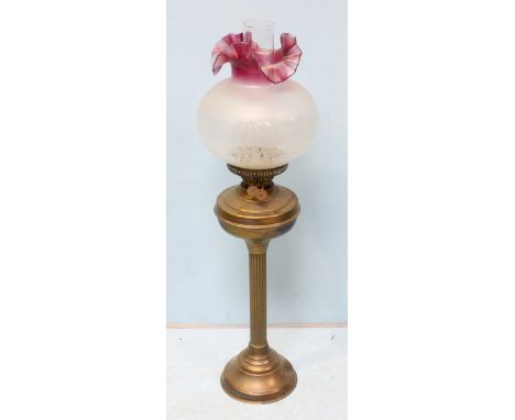 An Edwardian brass oil lamp, with globular glass bowl, raised on a reeded column to a turned, splayed base. 71cm high.