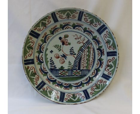 An 18th century English delft polychrome decorated charger probably Bristol, decorated with a fence pattern with floral bands