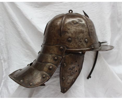 A 17th century German Zischagge, lobster tail helmet with a one piece hemispherical skull, with a pair of pendent cheek piece