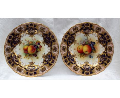 A pair of Royal Worcester porcelain cabinet plates, with a light pink and royal blue border, with gilt jewelling and scrolls,