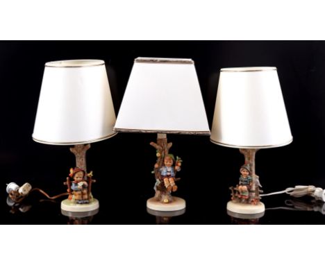 3 Goebel Hummel earthenware table lamp bases with boys sitting by the tree, numbers 224/I, 230 and 227, with upholstered shad
