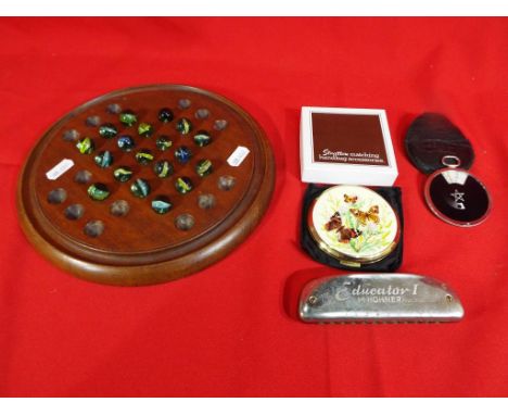 A wooden solitaire board with a quantity of marbles, a Hohner Educator 1 harmonica, a boxed Stratton powder compact and a Zei