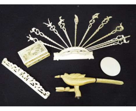 A collection of antique worked ivory to include a stand containing hat pins depicting various animals, a comb handle, trinket