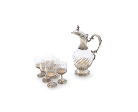 A WHITE METAL MOUNTED AND FLUTED GLASS LIQUEUR SET, comprising classical style claret-shaped ewer with raised leafy finial, a
