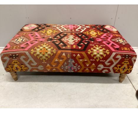 A large Contemporary rectangular footstool with antique polychrome Kilim upholstery on turned beech feet, width 124cm, depth 