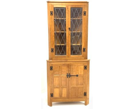 'Eagleman' oak corner cupboard,  with led glazed doors enclosing three shelves, panelled doors under enclosing another shelf,