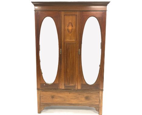 Edwardian inlaid mahogany double wardrobe, two oval mirrored doors enclosing interior fitted for hanging, one drawer under, r
