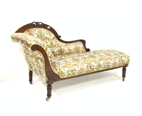 Late Victorian walnut chaise longue, with scroll ends and incised decoration, and carving to crest rail, upholstered in scrol