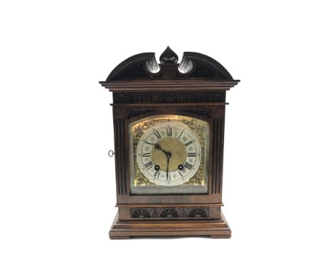 Late 19th century mantle clock in architectural walnut case, arched pediment with central leaf carved motif, enclosed by beve