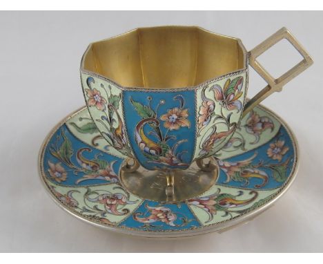 A Russian silver gilt cloisonne enamel cup of octagonal form on four feet with alternate blue and white panels, the saucer wi