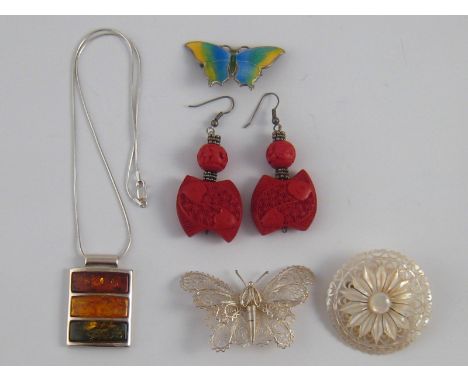 A mixed lot of white metal (tests silver) jewellery comprising an enamel butterfly brooch, an amber pendant and a filigree bu