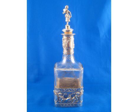 A silver mounted spirit decanter, a broad band around the base with putti at play, the glass square body with wheel engraved 