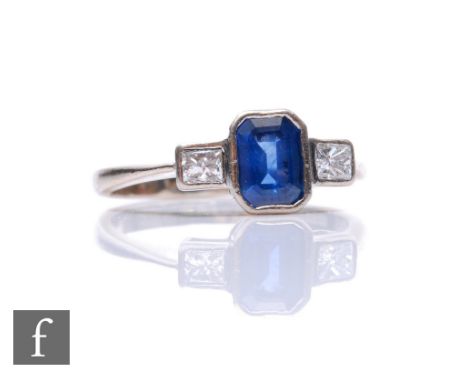 A hallmarked 18ct white gold sapphire and diamond three stone ring, central emerald cut sapphire, length 6mm, flanked by two 