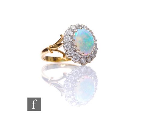 An 18ct hallmarked opal and diamond cluster ring, central oval opal, length 10mm, within a border of fourteen brilliant cut d