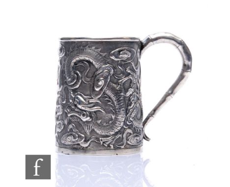 An early 20th Century Chinese small silver tankard with embossed dragon decoration terminating in bamboo style scroll handle,