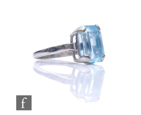 An 18ct white gold single stone aquamarine ring, claw set emerald cut stone to scrolled shoulders, weight 5g, ring size Q. 