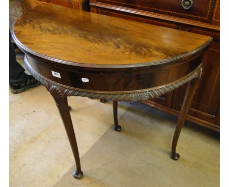 An Edwardian mahogany foldover card table, carved frieze and cabriole legs.