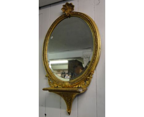 A Victorian carved giltwood and gesso oval wall mirror with shelf.