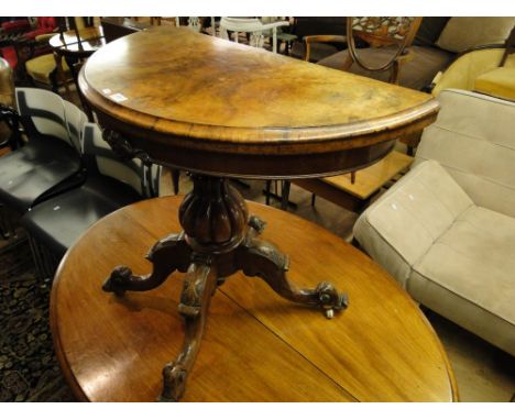 A Victorian figured walnut demi lune foldover card table, raised on a fluted centre column and carved sabre leg base.