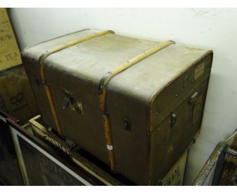 A Vintage steamer trunk with bentwood straps and brass mounts and various labels.