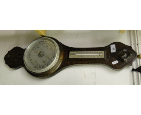 A wall barometer in carved oak case