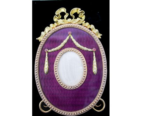 A silver gilt and enamel photograph frame in the Faberge style, marked London 1987, oval shape decorated with silver garlands