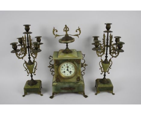 An Onyx and Ormolu clock garniture set, late 19th century, ormolu mounts to clock and candelabra standing on paw feet, painte