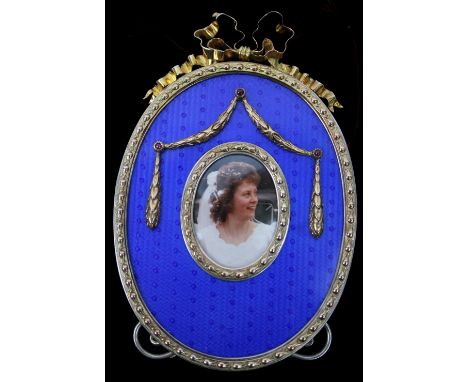 A silver gilt and enamel photograph frame in the Faberge style, marked London 1987, oval shape decorated with silver garlands