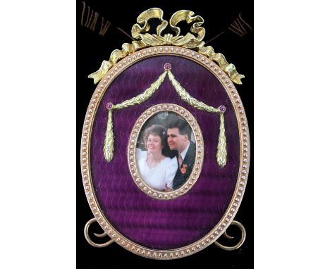 A silver gilt and enamel photograph frame in the Faberge style, marked London 1987, oval shape decorated with silver garlands