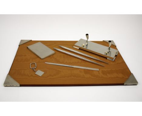 A silver desk set, comprising a desk blotter 1986, pen stand 1984, two pens 1985, letter opener 1986, note pad holder 1981 an