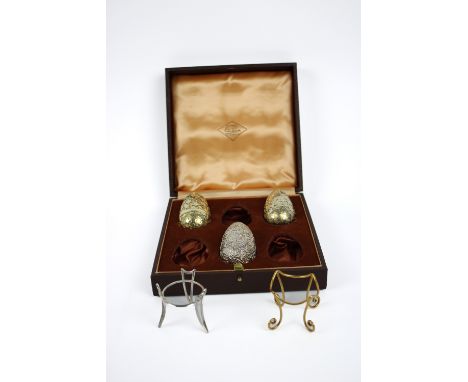 Three silver and silver gilt surprise eggs, marked London 1977 and 1975, together with two stands , in a fitted case, Markers