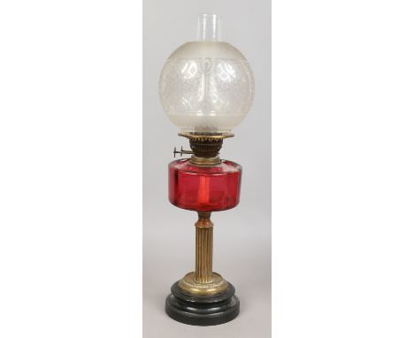 A brass column oil lamp with ruby glass font and frosted glass shade.