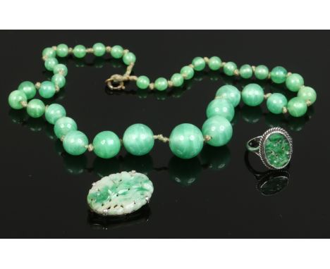 A white metal mounted pierced jade ring and ovoid brooch along with a jade coloured bead necklace.