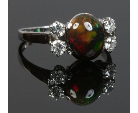 An 18ct white gold ring set with a large ovoid black opal flanked by two pairs of diamonds, size P.