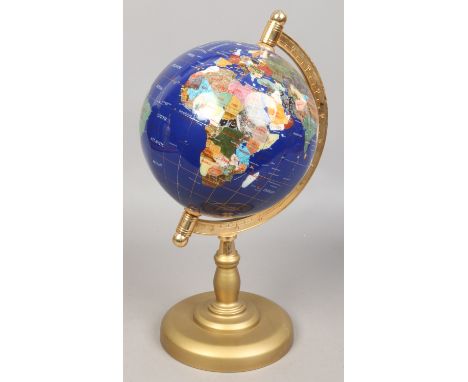 A decorative globe set with gem and hardstones, raised on gilt base.