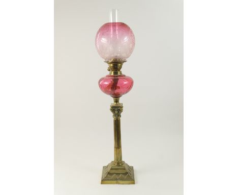 Edwardian brass and cranberry glass pedestal oil lamp, the globular shade etched with flowers in Art Nouveau style, swirl mou
