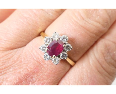 Ruby and diamond cluster ring, the oval cut ruby of approx. 0.5ct, in a four claw stepped mount and bordered with eight small