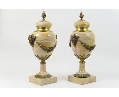 Pair of French ormolu mounted marble cassoulet urns, with flame finial, rams mask and floral garland appliques, over a square