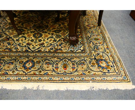 Kashan woollen carpet, having a fawn field with a sky blue central medallion dispersed with palmettes, and with a palmette bo
