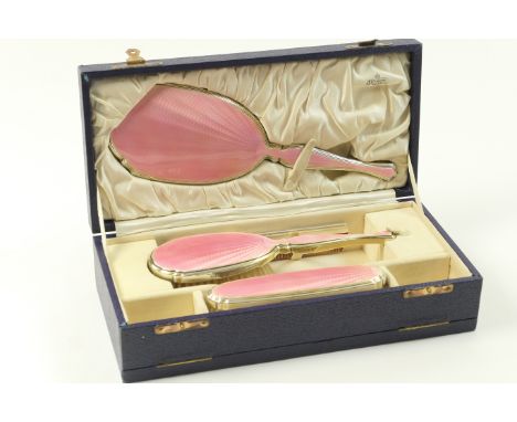 Pink enamelled silver gilt vanity set by J C Vickery, Chester 1931/32, comprising hand mirror, hair brush and clothes brush, 