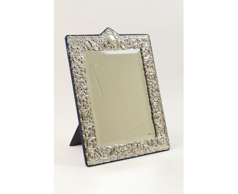 Modern sterling silver dressing table mirror, the rectangular bevelled glass plate bordered with a facing of repousse silver 